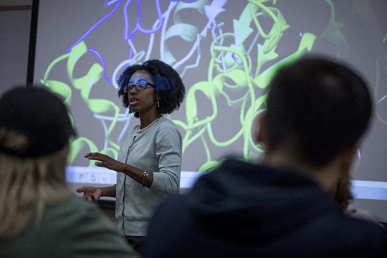 an African American woman teaches at a whiteboard