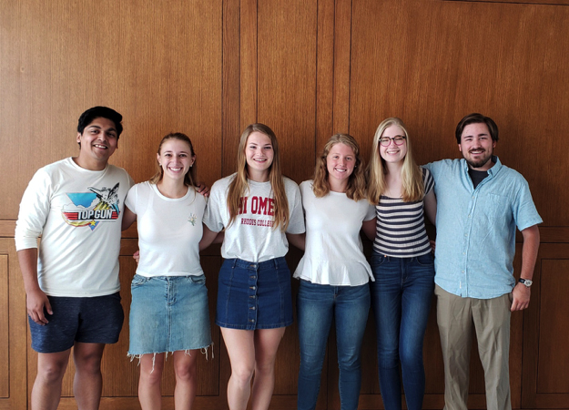 two male and four female students stand arm-in-arm