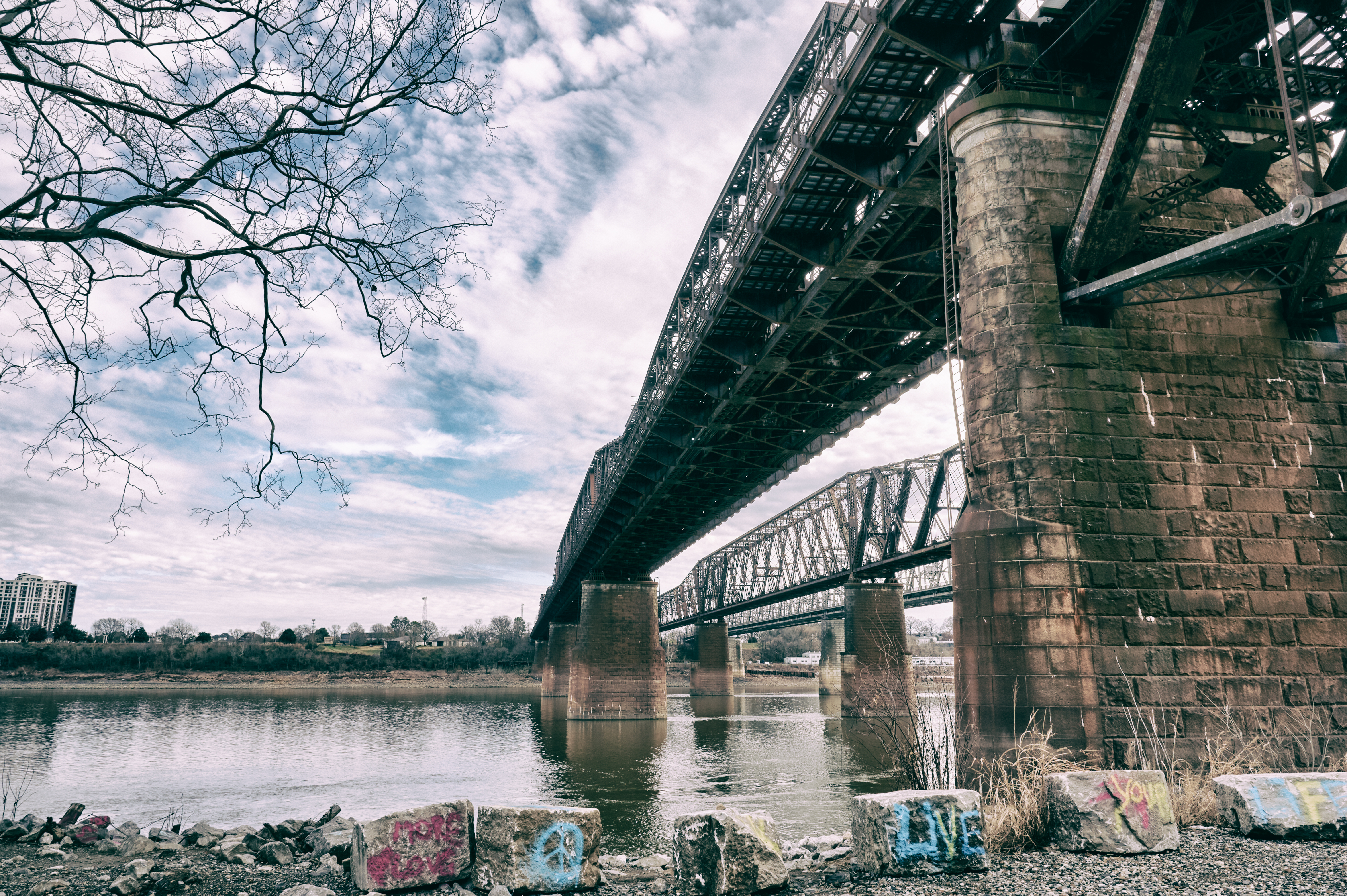 a bridge over a large river with graffiti under it