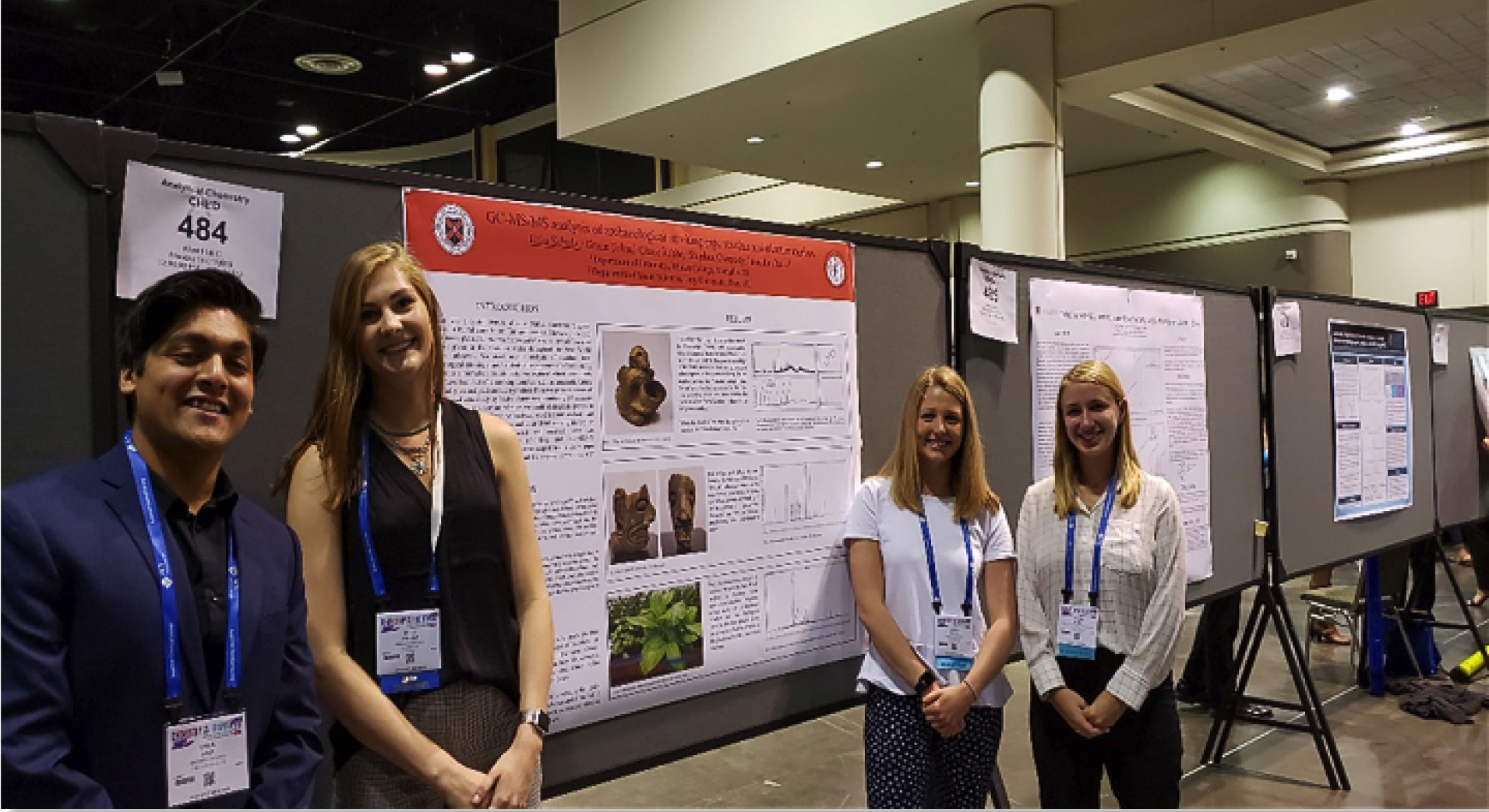 one male and three female students in front of a poster presentation