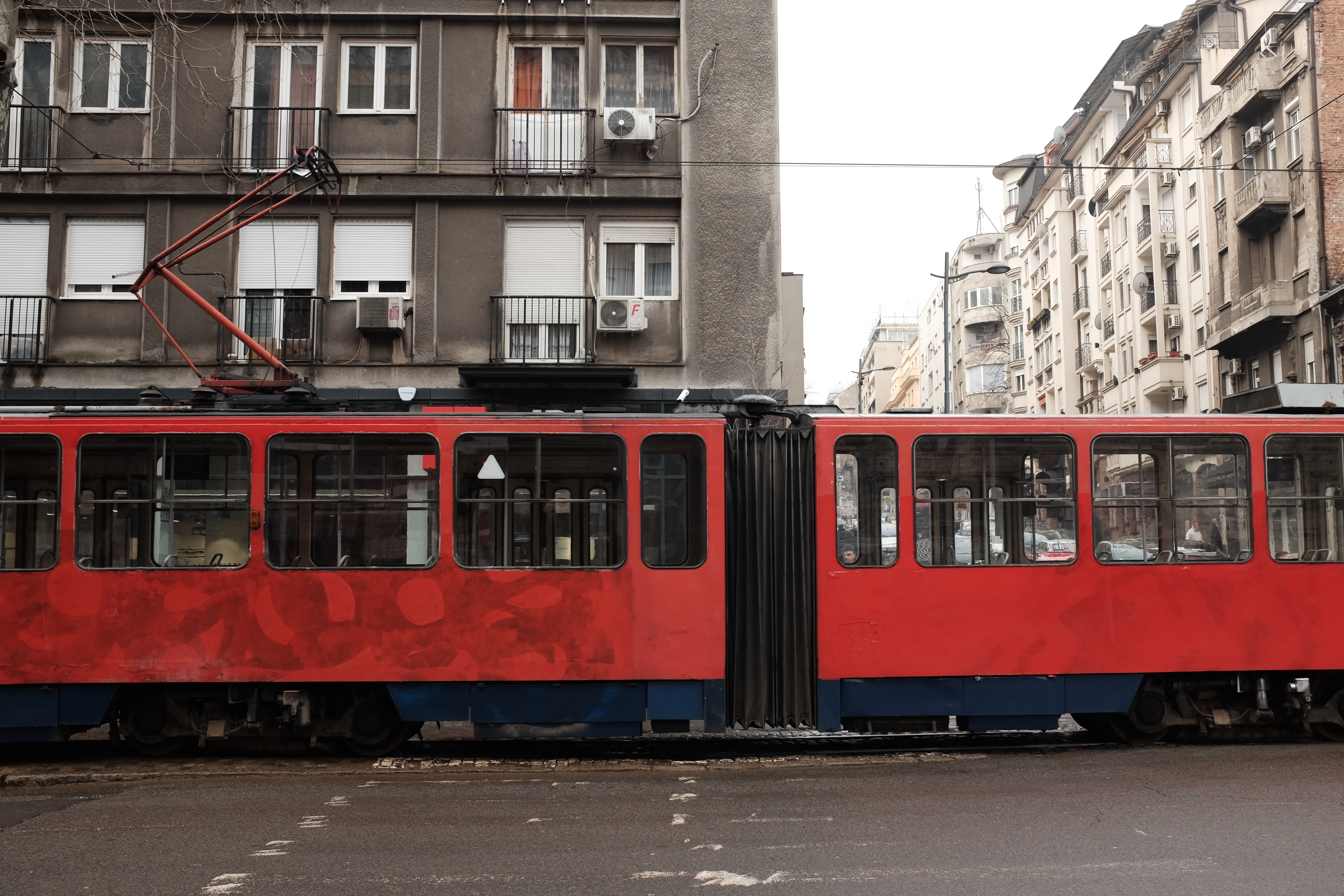 A bright red streetcar going through a city. 