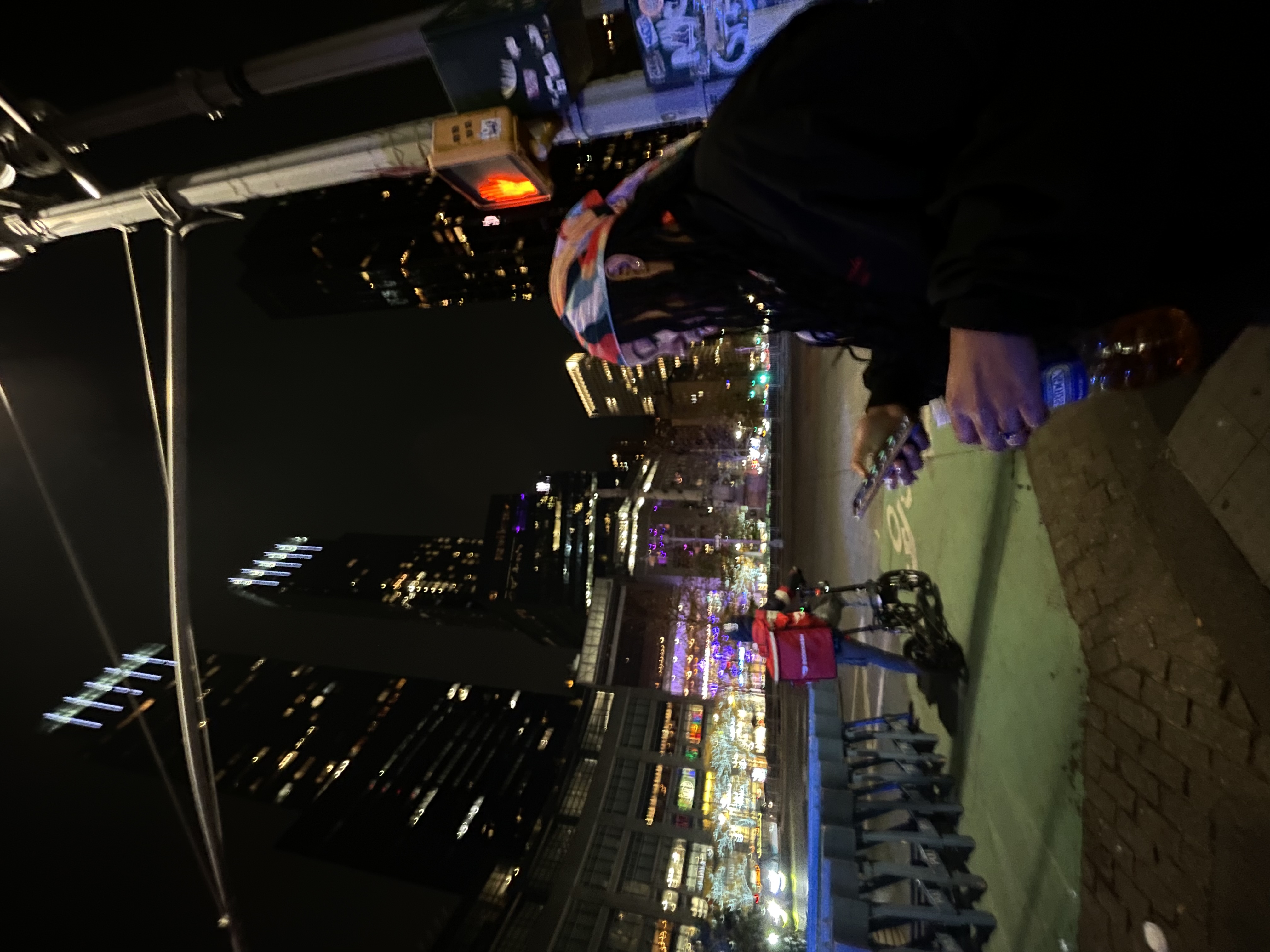 A girl checks her phone while going on a night walk in the city.