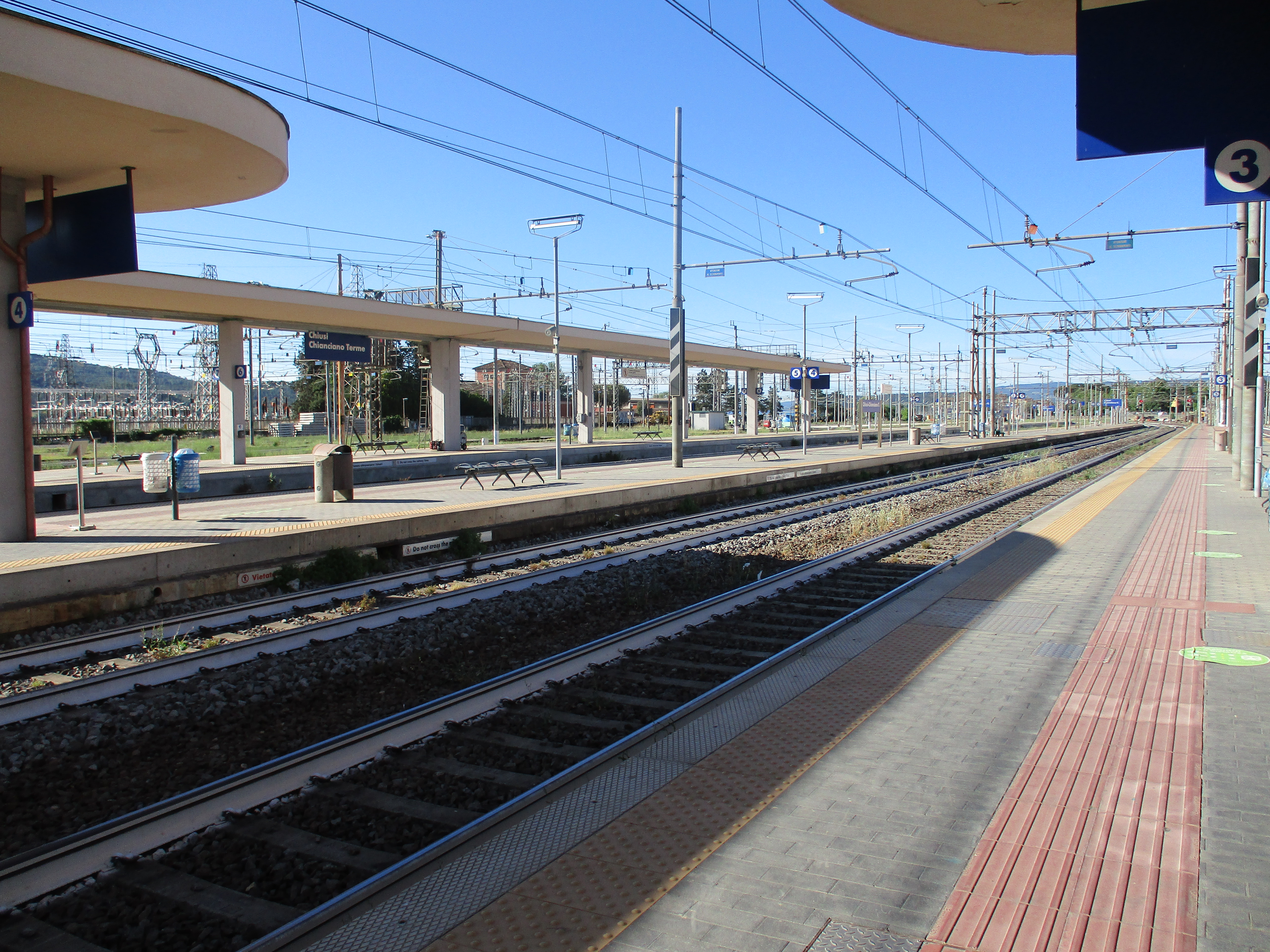 An empty train station underneath a clear blue sky. 