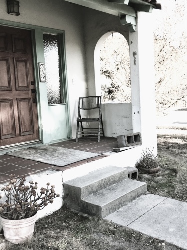 A lone chair on an empty porch. 