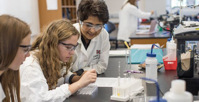 a female professor helps a student in a lab