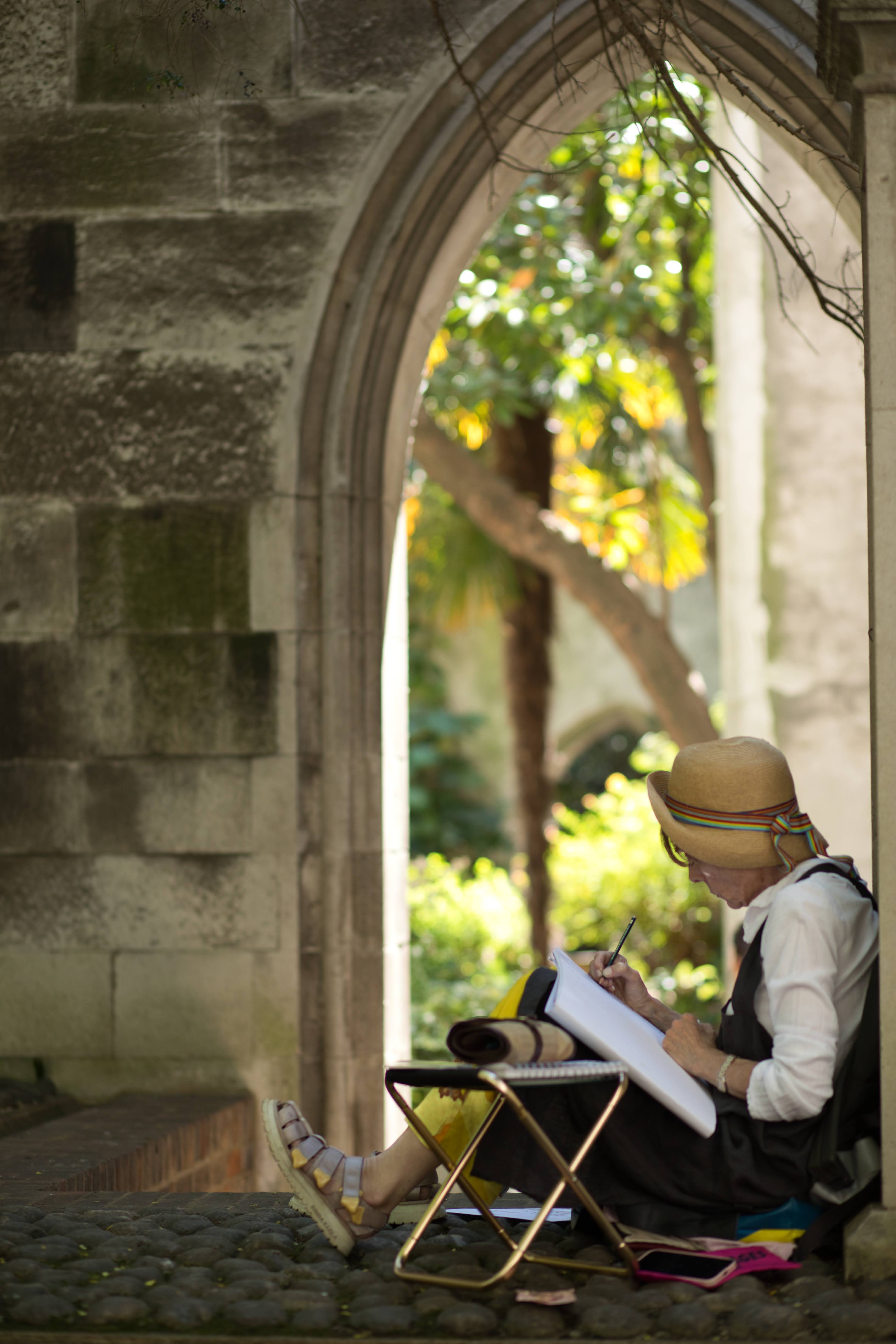 A woman reading under a stone archway