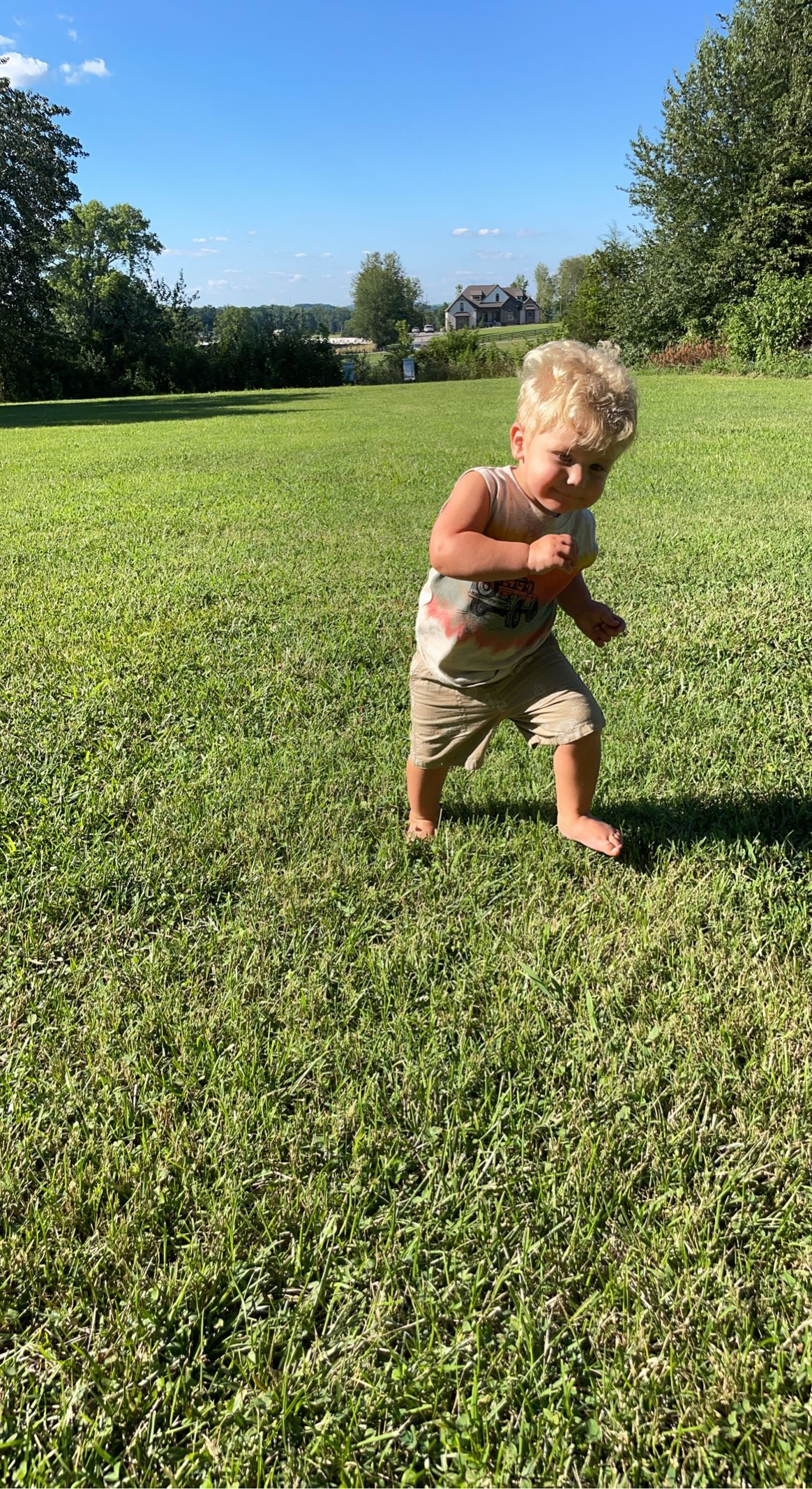 a young boy runs on a grassy field