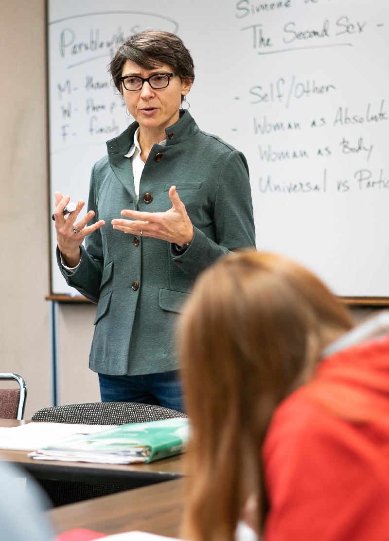 A professor talks with a student in class