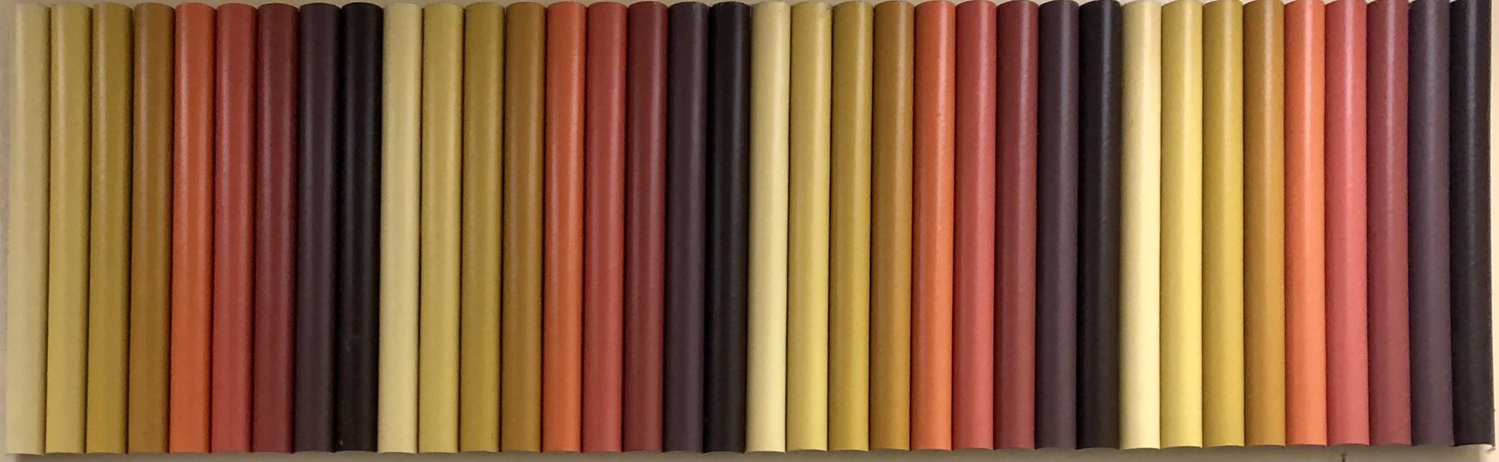 Sculpture of yellow, orange, red, and brown cardboard tubes aligned vertically. 