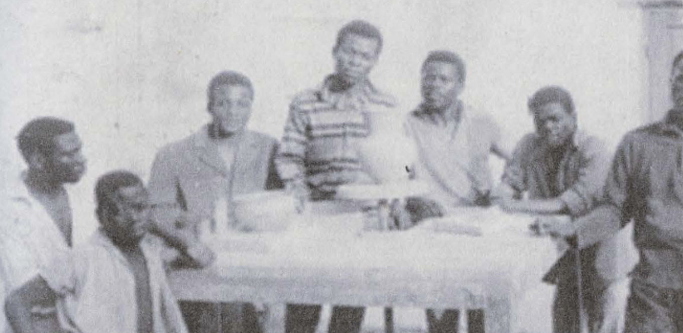 Group of men posed around a table.