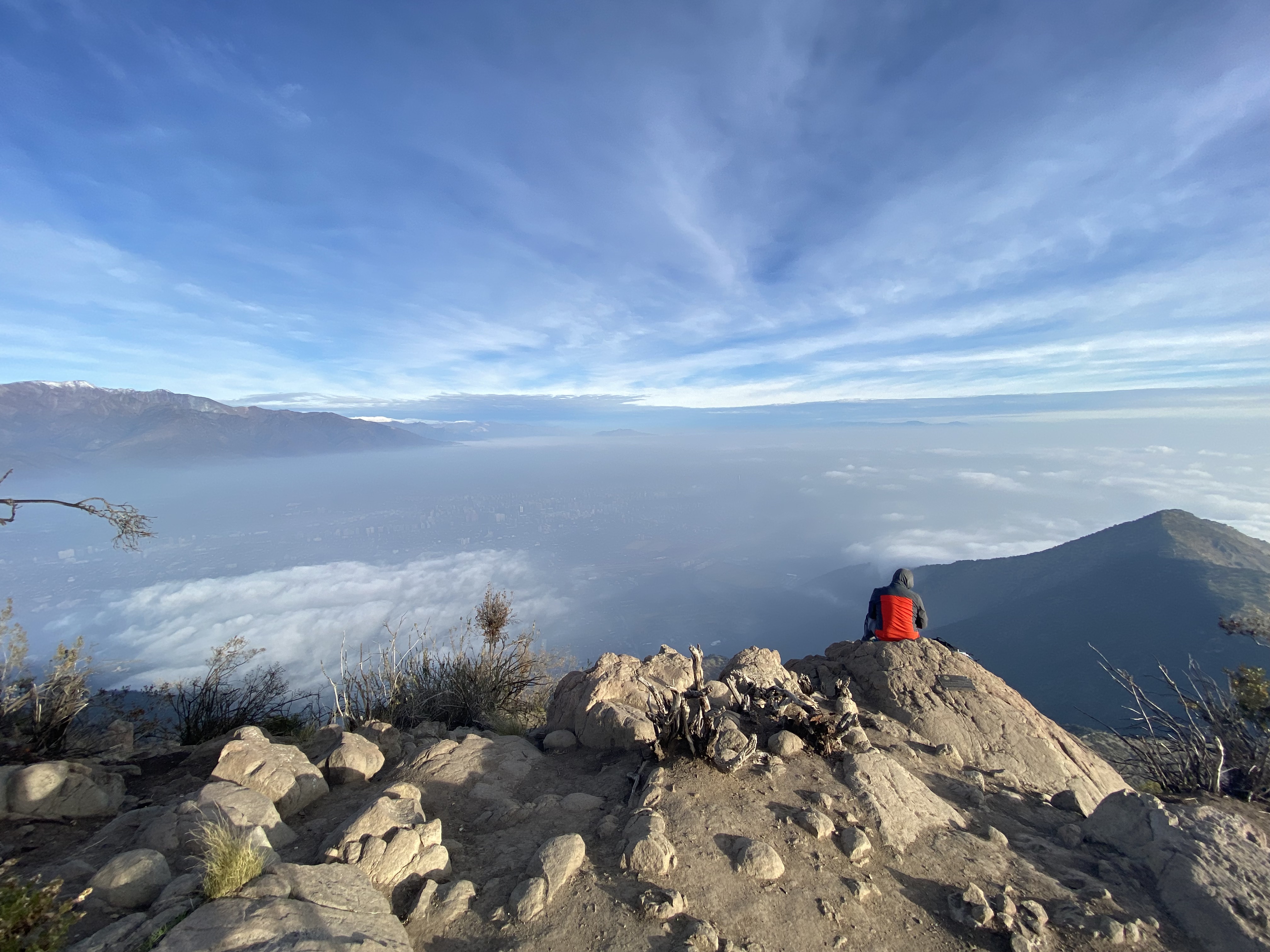 a lone imge on a hilltop with clouds below