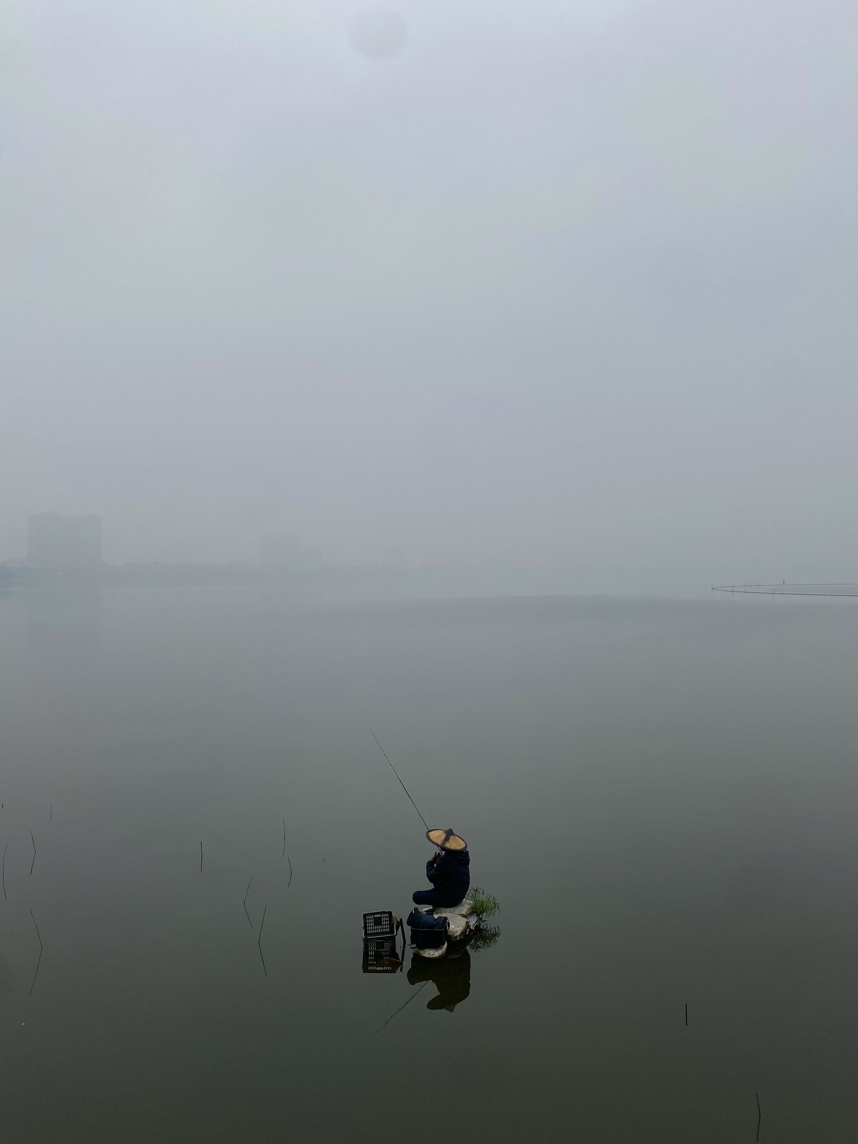 a person fishing on a foggy morning