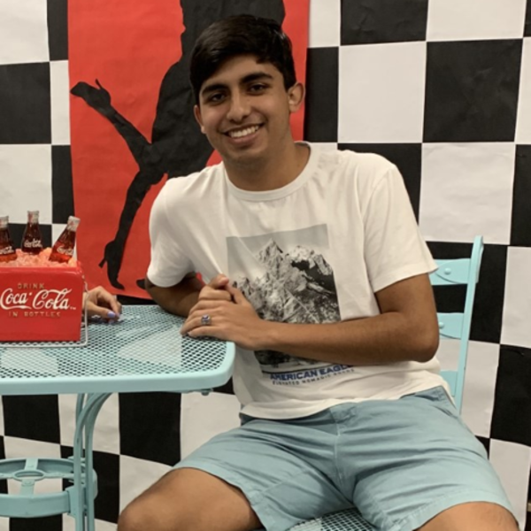 a young man with dark hair sits at a table