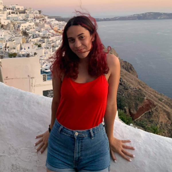 a young woman poses against a Greek skyline on the coast