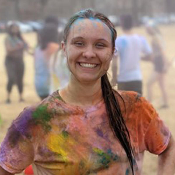a young woman spattered with bright colors during a Holi Festival