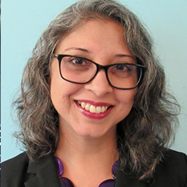 a woman with glasses and wavy hair smiles at the camera