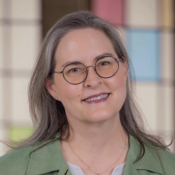 A woman with shoulder-length brown hair and glasses