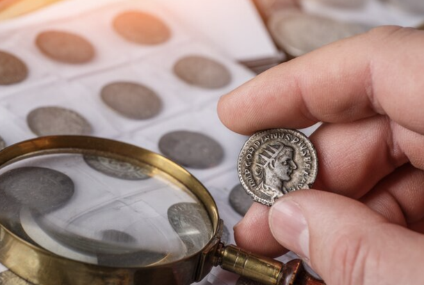 A visual representation of numismatics. In image: an individual holding up a coin for analysis