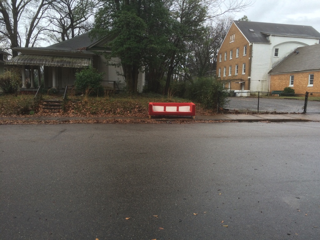 an abandoned couch in front of a rundown hose