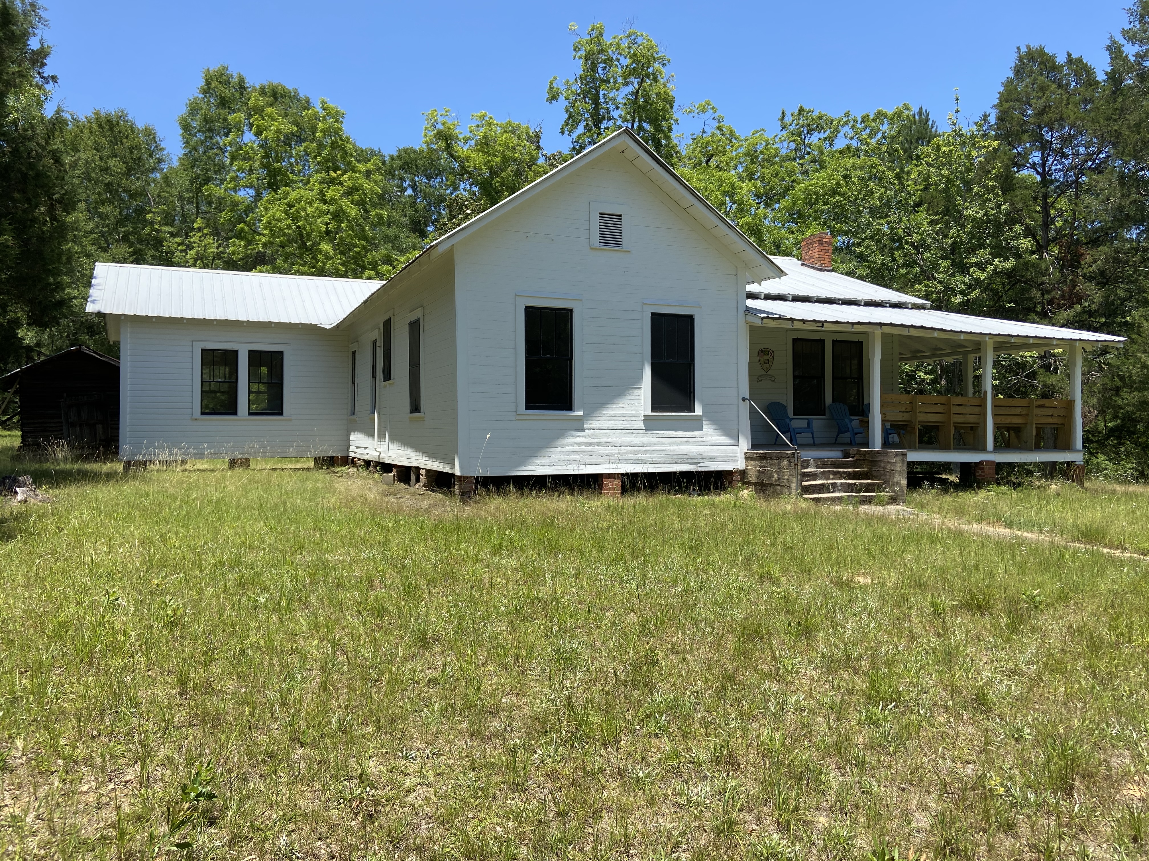 a white frame house with a porch in the country