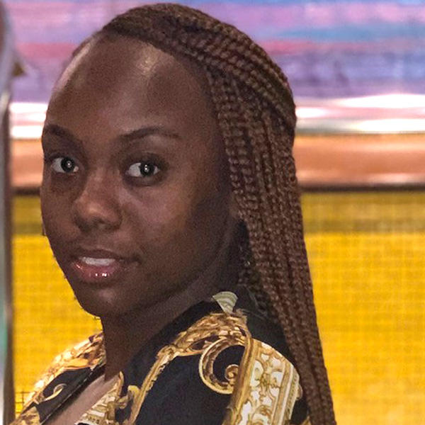 an African American woman with long braided hair smiles at the camera