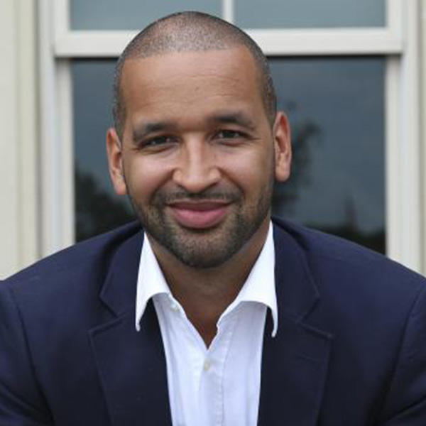 an African American man in a blue suit jacket smiles at the camera