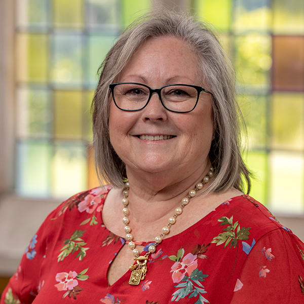 a woman in glasses and a red flowered dress