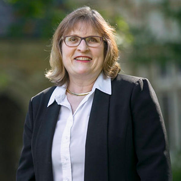 a woman in a black suit wearing glasses